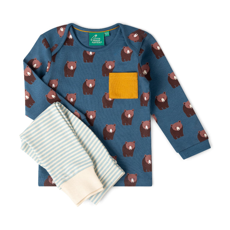 A children's two-piece pajama set laid flat on a white background. The long-sleeve top is slate blue with an allover brown bear print and a solid mustard yellow chest pocket.
