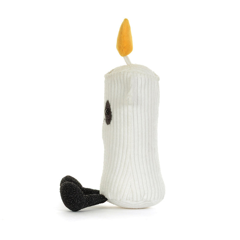 A white ribbed plush candle toy with a yellow flame on top, a small black embroidered eye, and a black textured foot, photographed on a clean white background.
