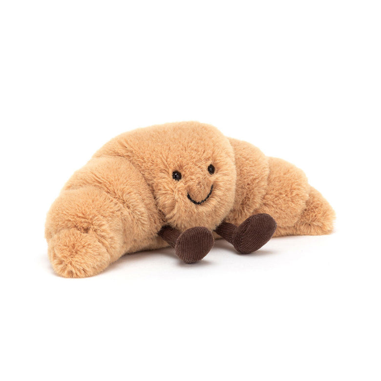 Plush toy shaped like a croissant with a smiling face on a white background