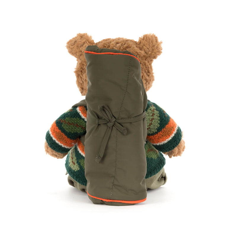 Stuffed bear wearing a green coat with a striped sweater on a white background