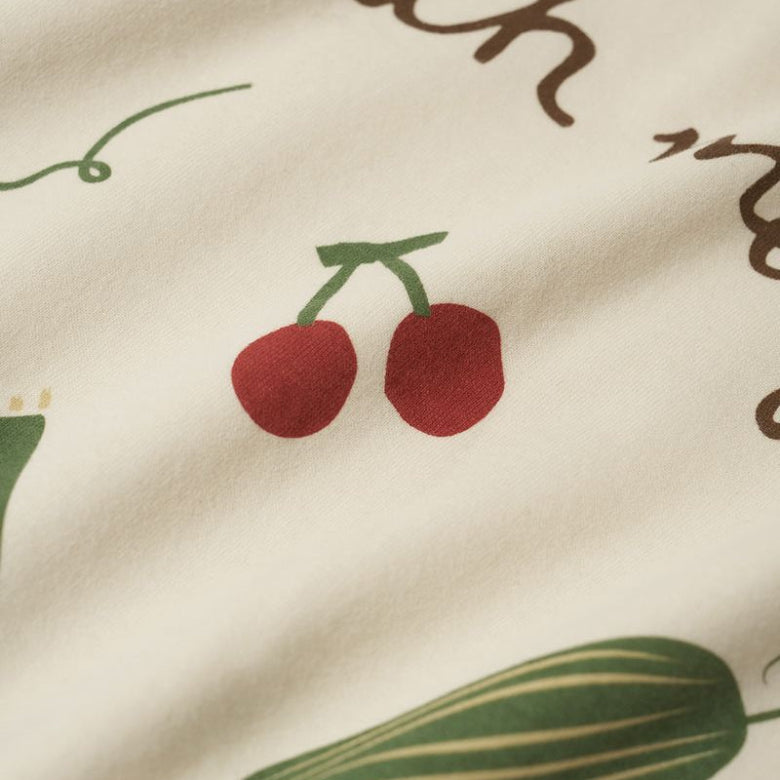 Close-up of fabric with cherry and cucumber illustrations on a beige background.