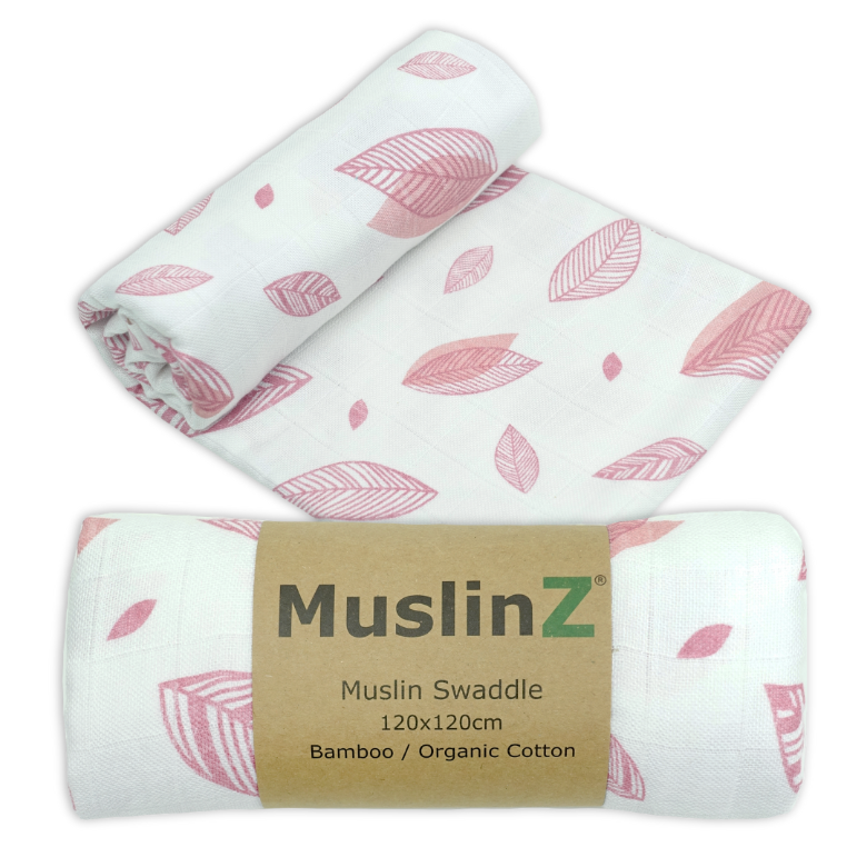 Three rolled muslin swaddles with a pink leaf pattern on a white background, with one swaddle wrapped in a brown paper band labeled 'MuslinZ'.