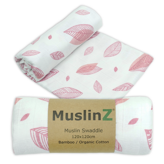 Three rolled muslin swaddles with a pink leaf pattern on a white background, with one swaddle wrapped in a brown paper band labeled 'MuslinZ'.