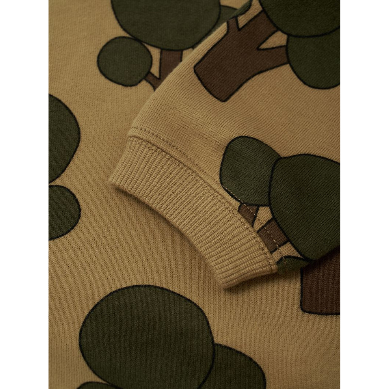 Close-up of a ribbed knit sleeve cuff on a beige sweater with an allover tree print in olive green and brown.