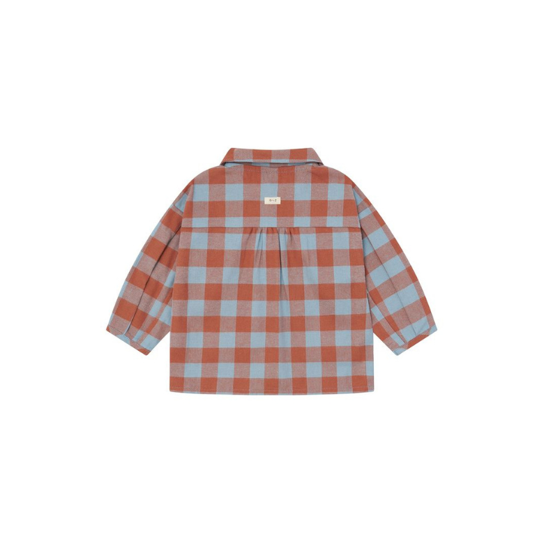 A children's long-sleeve plaid button-up shirt shown flat against a solid white background. The shirt features a checkered pattern of terracotta orange and light blue, with a small beige brand label on the back collar.