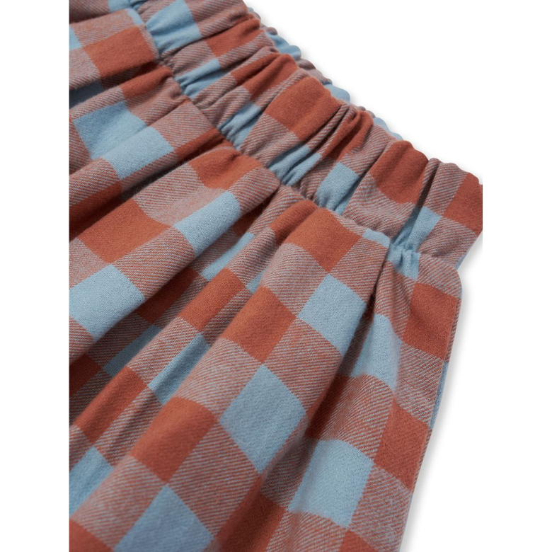 Close-up of a plaid fabric garment, showing an elasticized waistband with a checkered pattern in terracotta orange and light blue on a white background.