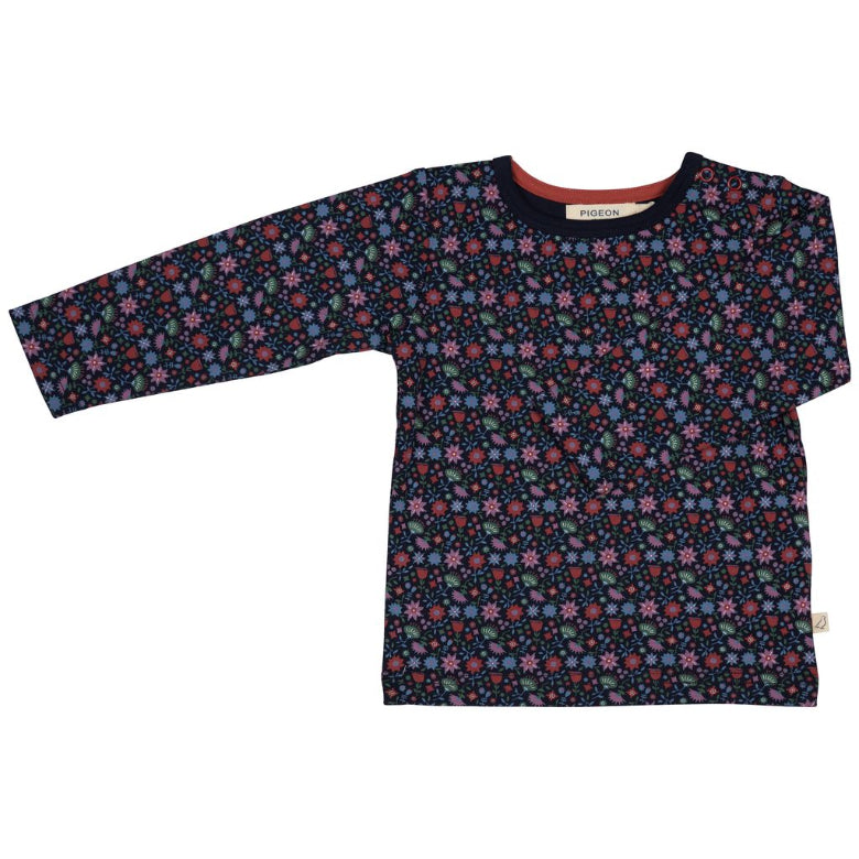 A long-sleeve children's top with an all-over floral pattern in pink, blue, and green on a dark navy background, featuring a solid navy collar with a red inner lining.