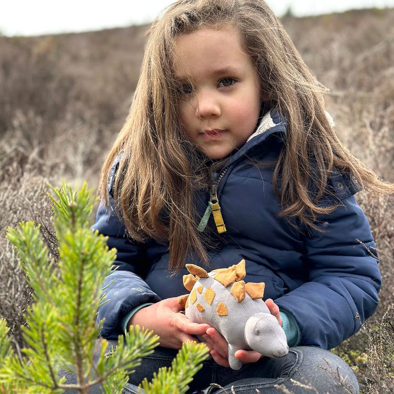 Child holding a stuffed animal in a natural setting