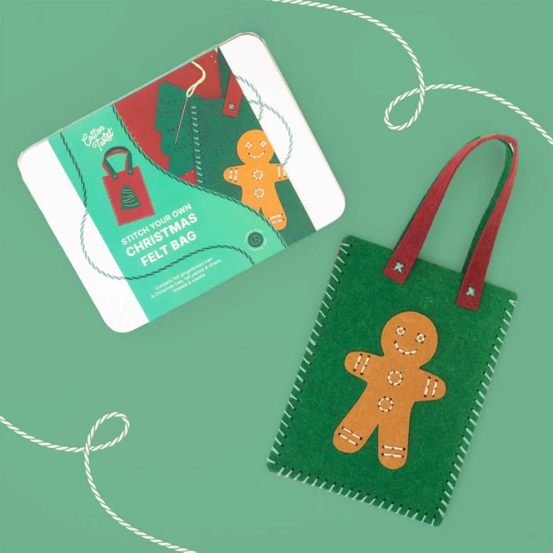 A felt Christmas bag with a gingerbread man design and red handles, shown next to its printed packaging card on a mint green background with decorative white string.